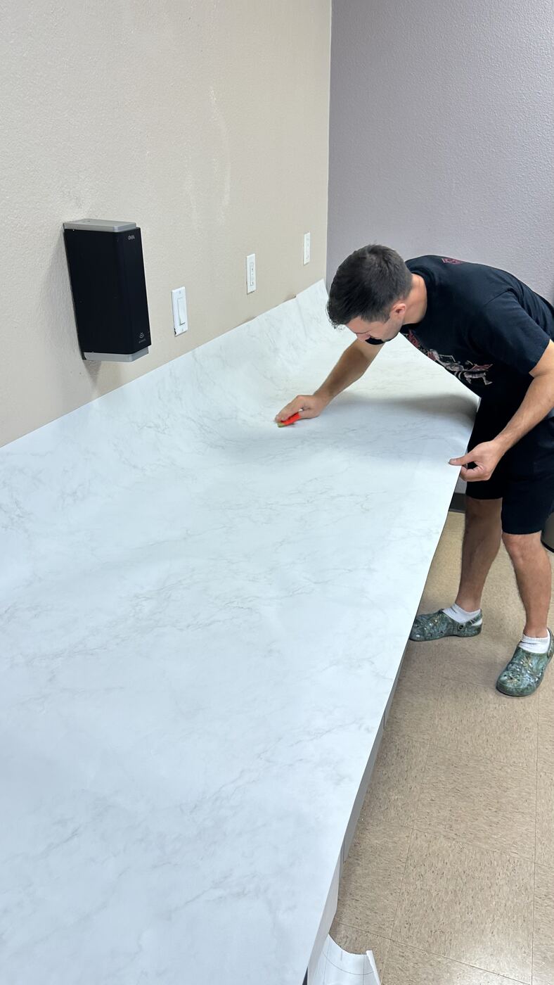 Bodaq marble film being applied and smoothed onto countertop
